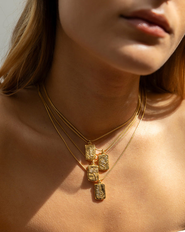 Cuello de mujer luciendo los collares Amuletos diente de león, helecho, lavanda, y magnolia