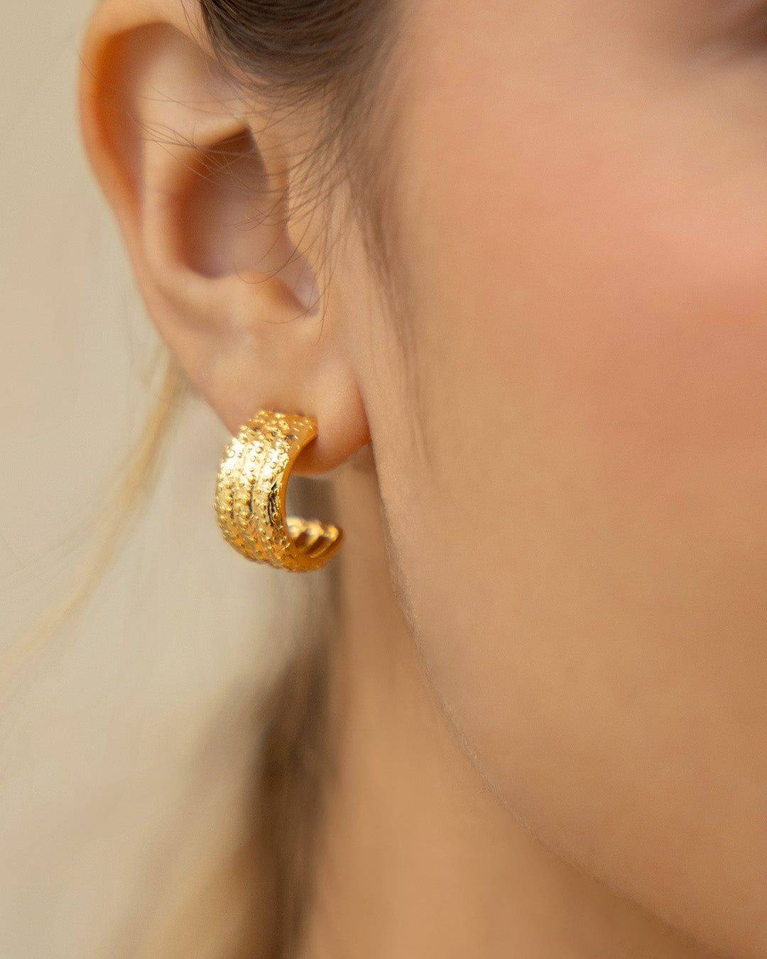 Acercamiento a oreja de mujer luciendo las candongas Aura bañadas en oro 24K 