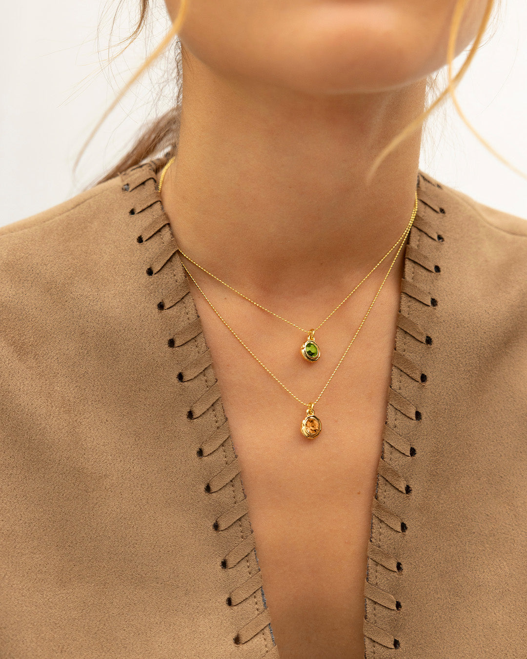 Cuello de mujer luciendo collares Cristales con dijes verdes y ambar
